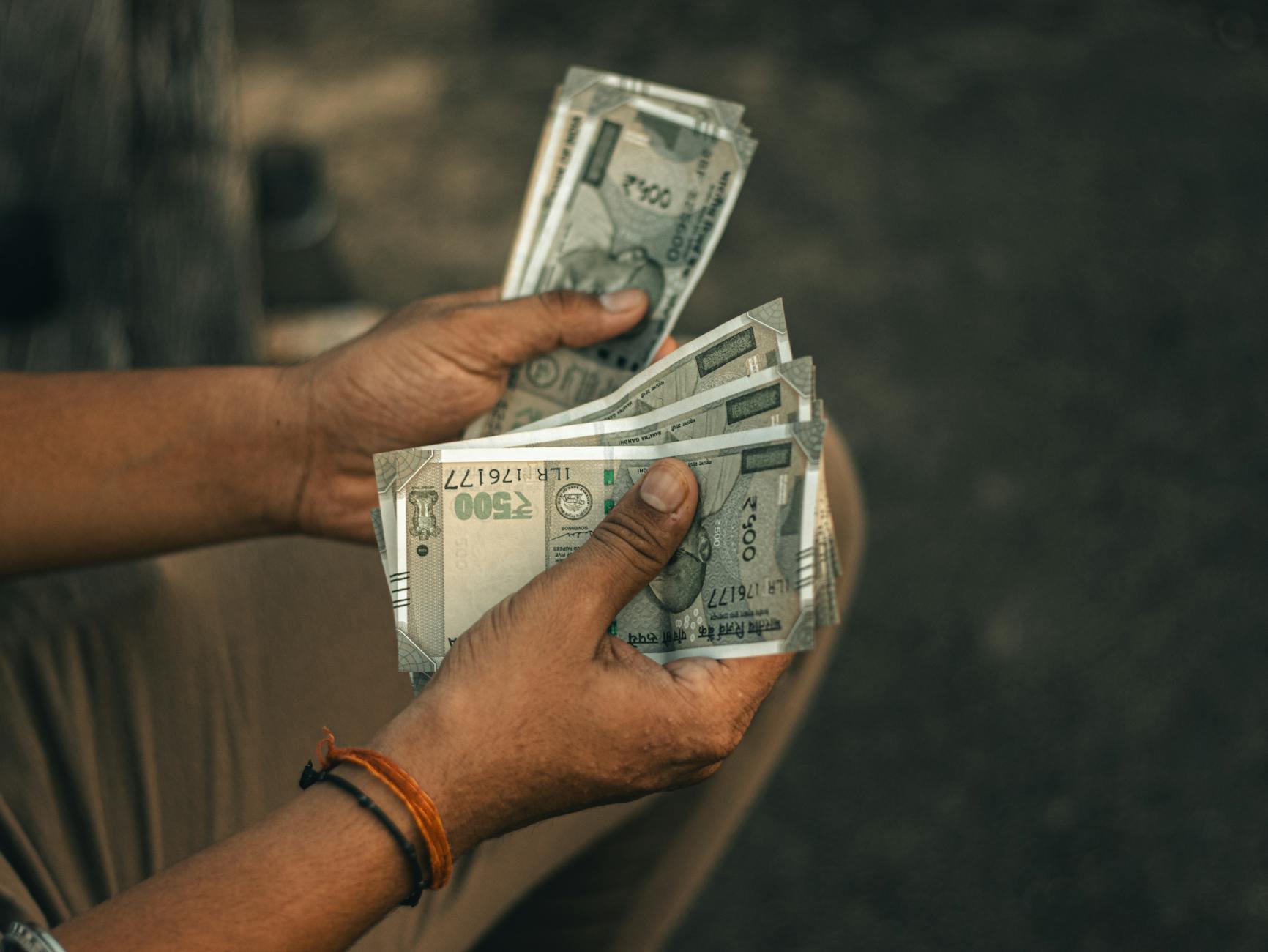 Hands counting 500 Indian Rupee notes