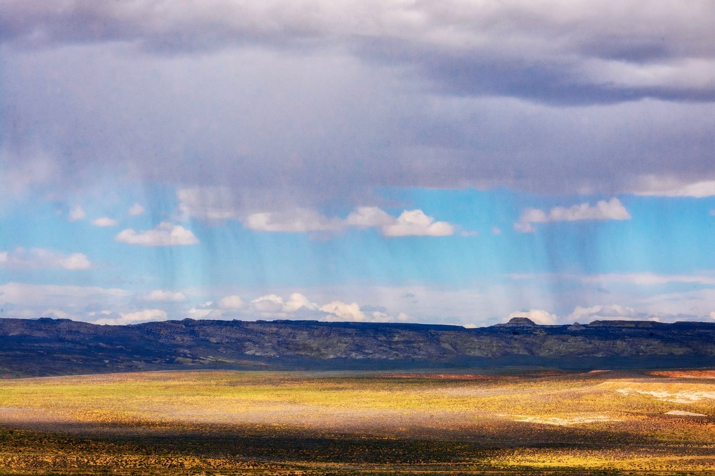 A scenic view of a vast field under a rainy sky in Page, Arizona, highlighting dramatic weather.